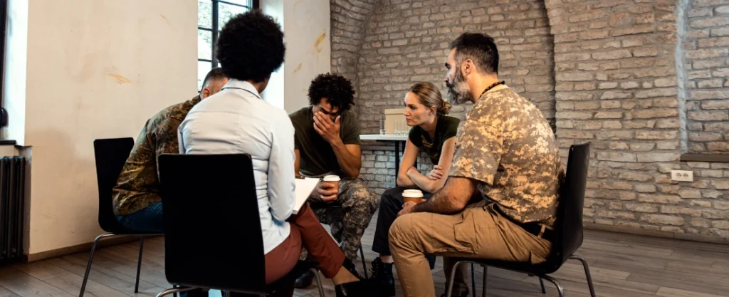 Image of a group therapy session with a counselor and 4 military members - Does TRICARE Reserve Select Cover Addiction Treatment - TRICAREREHABS
